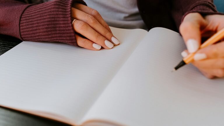 A person’s hands writing in an open notebook